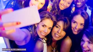 Group of friends taking a joyful selfie on a night out in Atlanta, capturing moments before boarding a luxury limousine.